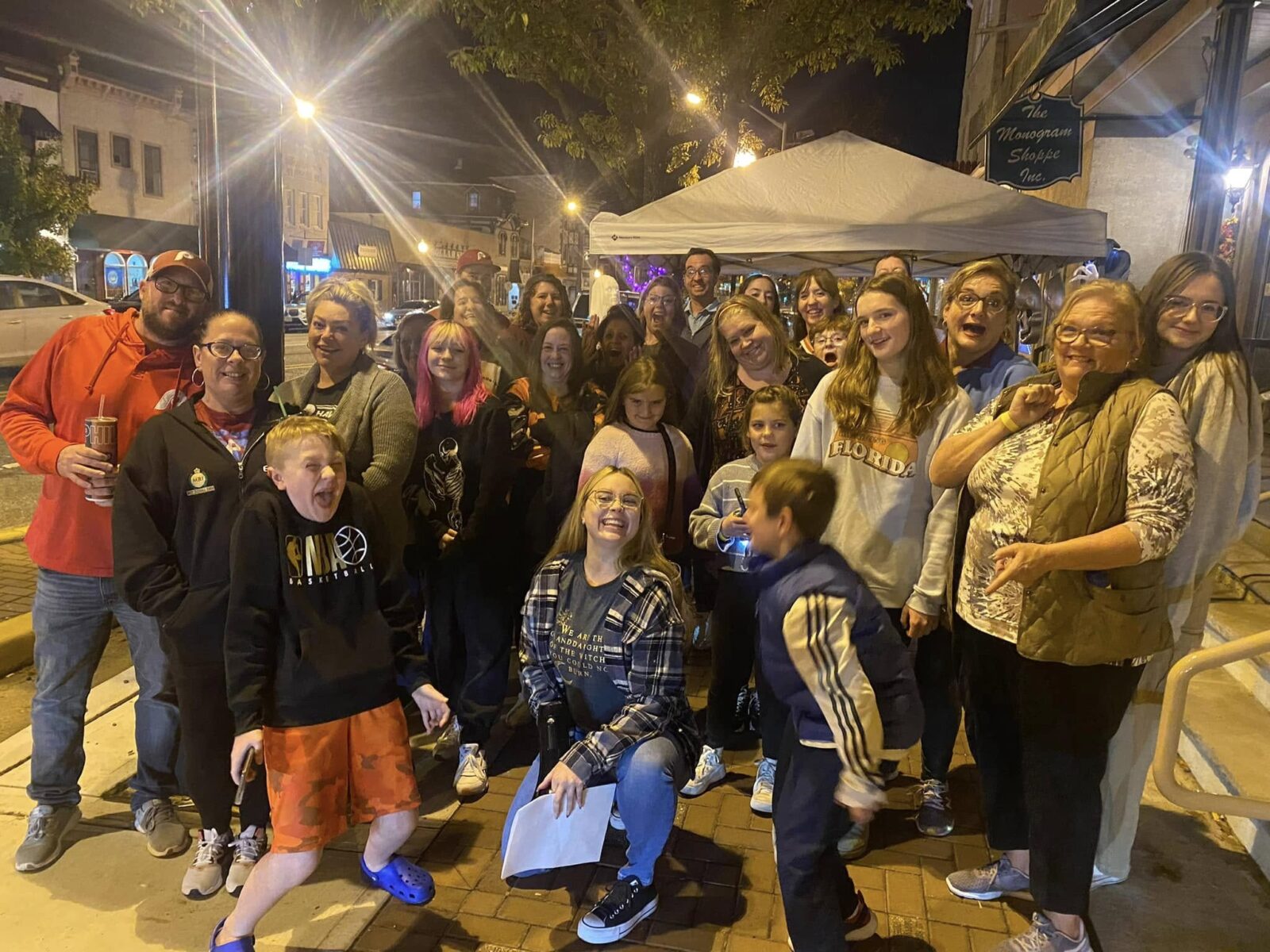 Ghost Tour Group Downtown Woodbury Night A large group poses at night on a downtown sidewalk outside The Monogram Shoppe.